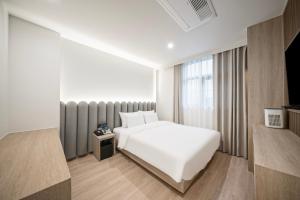 a hotel room with a white bed and a window at Gyeongju Poverta Hotel in Gyeongju
