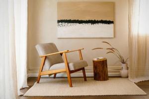 una sedia seduta su un tappeto accanto a un tronco d'albero di The Honey Barn, Wabi-Sabi Cottage Byron Hinterland a Clunes Altre 12 foto