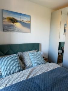 a bedroom with a blue bed and a painting on the wall at Apartament nr 14 Łeba in Łeba