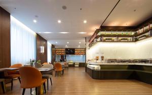 un restaurante con bar, mesas y sillas en Mövenpick by Accor Binjiang Nanjing, en Nanjing