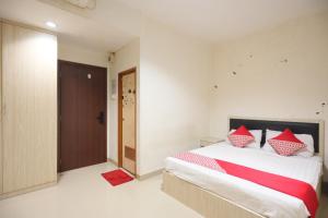 1 dormitorio con 1 cama con almohadas rojas y blancas en OYO 93667 Penginapan Pelangi, en Batam Centre