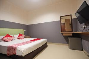 Schlafzimmer mit einem Bett mit roten Kissen und einem TV in der Unterkunft OYO 93667 Penginapan Pelangi in Batam Center