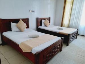 two beds sitting next to each other in a room at Lux Suites Nyali Beachfront Apartments in Mombasa +16 photos