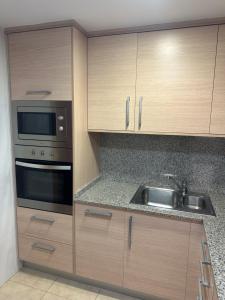 una cocina con armarios de madera y fregadero en Apartamentos L'Ainsa en Aínsa