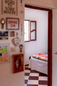 Habitación con cama, ventana y suelo a cuadros. en Ayour Hostel, en Sidi Kaouki