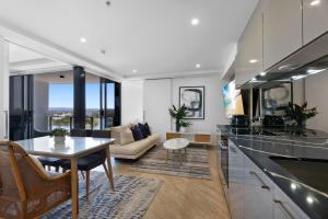 a kitchen and living room with a table and a couch at Avalon Apartments - QStay in Gold Coast