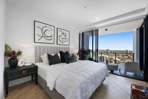 a bedroom with a large white bed and a large window at Avalon Apartments - QStay in Gold Coast