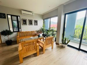 ein Wohnzimmer mit einem Tisch, Stühlen und Fenstern in der Unterkunft The Light Hotel in Hạ Long