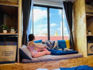una mujer sentada en una cama mirando por la ventana en Private house with Pagoda view, near Grand Palace, en Bangkok