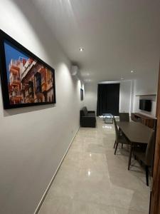 sala de estar con mesa de comedor y TV en la pared en Smart 1 Bedroom Apartment in Noah Apartments, Gzira en Il-Gżira