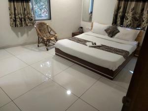 um quarto com uma cama e uma cadeira em Surbhi Hotel And Restaurant em Rajkot