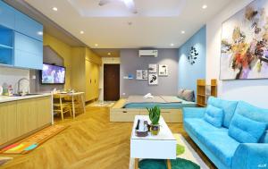 - un salon avec un canapé bleu et un lit dans l'établissement Harmony Vinhomes D'Capitale, à Hanoï