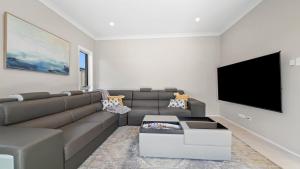 sala de estar con sofá y TV de pantalla plana en Seachange Umina- Modern, close to shops, beach, en Umina