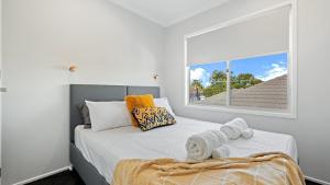 1 dormitorio con 1 cama con toallas en Seachange Umina- Modern, close to shops, beach, en Umina