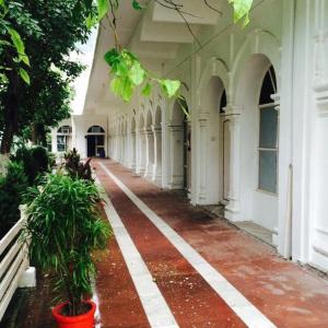 an empty hallway of a white building with plants at Hotel Bhajgovindam in Haridwār