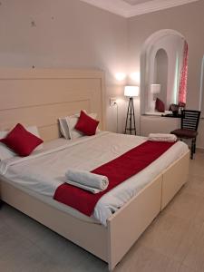 a bedroom with a large bed with red and white pillows at Hotel Bhajgovindam in Haridwār