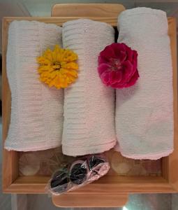 trois serviettes sur une étagère avec des fleurs sur elles dans l'établissement Hotel Bhajgovindam, à Haridwar