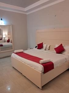 a bedroom with a large bed with red pillows at Hotel Bhajgovindam in Haridwār