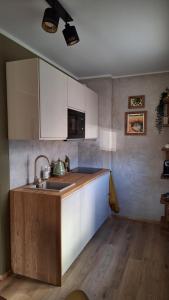 una cocina con armarios blancos y fregadero en Promenādes apartamenti, en Talsi