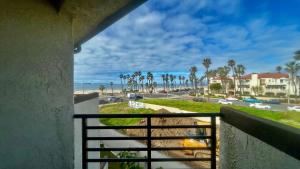 a balcony with a view of the beach and palm trees at Huntington Beach Inn in Huntington Beach