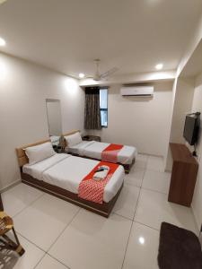 een slaapkamer met 2 bedden en een tv. bij Surbhi Hotel And Restaurant in Rajkot