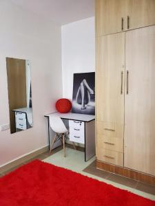Zimmer mit einem Schreibtisch und einem roten Teppich in der Unterkunft macdade apartment in Nairobi
