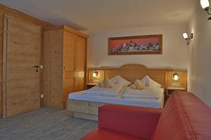 a bedroom with a bed and a red couch at Pension Schrempfgut in Flachau
