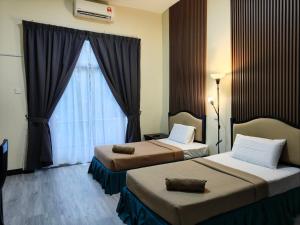 a hotel room with two beds and a window at TERENGGANU EQUESTRIAN RESORT (PADDOCK INN) in Kuala Terengganu