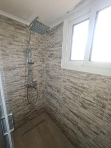 uma casa de banho com um chuveiro e uma parede de tijolos em Nea Peramos Large Apartment Near the Beach em Nea Peramos