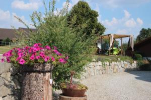 Una cesta de flores rosas en un tronco de árbol. en Pension Kramerhof, en Taufkirchen