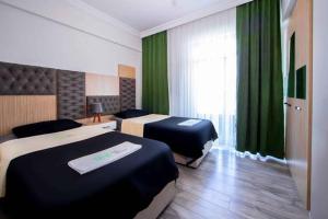 2 łóżka w pokoju hotelowym z zielonymi zasłonami w obiekcie seyir royal w mieście Balqash