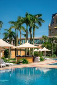 a swimming pool with palm trees and umbrellas at Four Seasons Hotel Macao, Cotai Strip in Macau