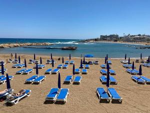 een groep strandstoelen en parasols op een strand bij Cozy ground floor appartment with communal pool in Paralimni