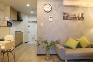 a living room with a couch and a clock on a wall at Comma House Minaminagasaki 202 in Tokyo
