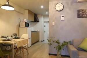 a living room with a couch and a clock on the wall at Comma House Minaminagasaki 202 in Tokyo