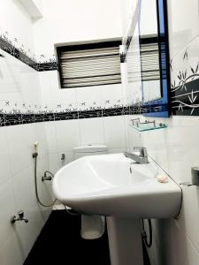 a white bathroom with a sink and a mirror at Grand Crown Hotel in Anuradhapura