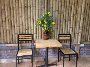 uma mesa com duas cadeiras e um vaso com flores em Cat Ba Island Garden Homestay - Papillon em Ilha de Cát Bà