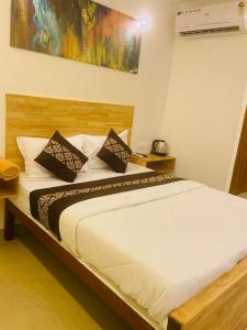 1 dormitorio con 1 cama blanca grande y 2 almohadas en RAINBOW ROOMS, en Kozhikode