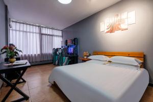 a bedroom with a large white bed and a table at Chengdu Dreams Travel International Youth Hostel in Chengdu