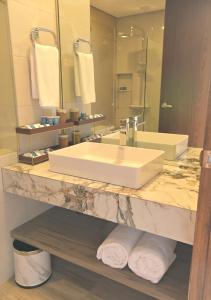 a bathroom with a sink and a large mirror at Magarra Hotel in Orani