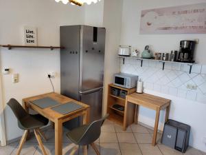 a kitchen with a table and a stainless steel refrigerator at Einzelwohnung im EG mit Terrasse und AC in Osterburg Siedlung