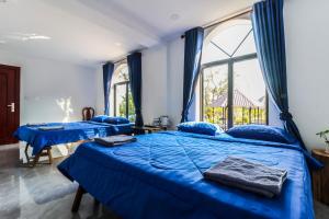 dwa niebieskie łóżka w pokoju z oknem w obiekcie Kampot Hill Lodge w mieście Kâmpôt