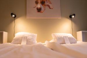 a bed with two pillows and a picture of a dog at Slottshotellet Annex in Kalmar