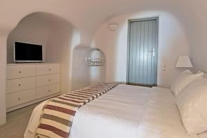 a white bedroom with a bed and a tv at SEACREST VILLA-VOLCANO VIEW in Oia