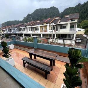 YouLuvHomestay Ipoh في ايبوه: مقعد على شرفة مبنى به بيوت