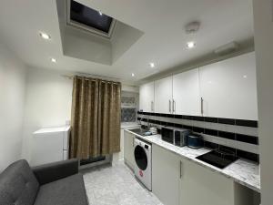 a kitchen with white cabinets and a washer at 4TH Studio Flat a Family Luxury London Home A Fully Equipped and furnished Studio With a King Size Bed And a Futon-Sofa Bed A Baby Cot A Kitchenette With a Private Toilet and Bath a Garden For up to 4 Guests and Free Parking in Lewisham
