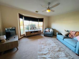 a living room with a blue couch and a tv at Sea Renity - Pet Friendly in Robe