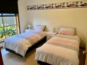 two beds in a room with a window at Sea Renity - Pet Friendly in Robe