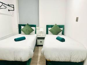 2 Betten in einem Zimmer mit grünen Kissen darauf in der Unterkunft Coastal Charm Comfort Home in Margate in Margate