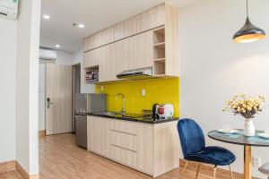 a kitchen with a counter and a table with a blue chair at Laurel Da Nang Apartment in Da Nang